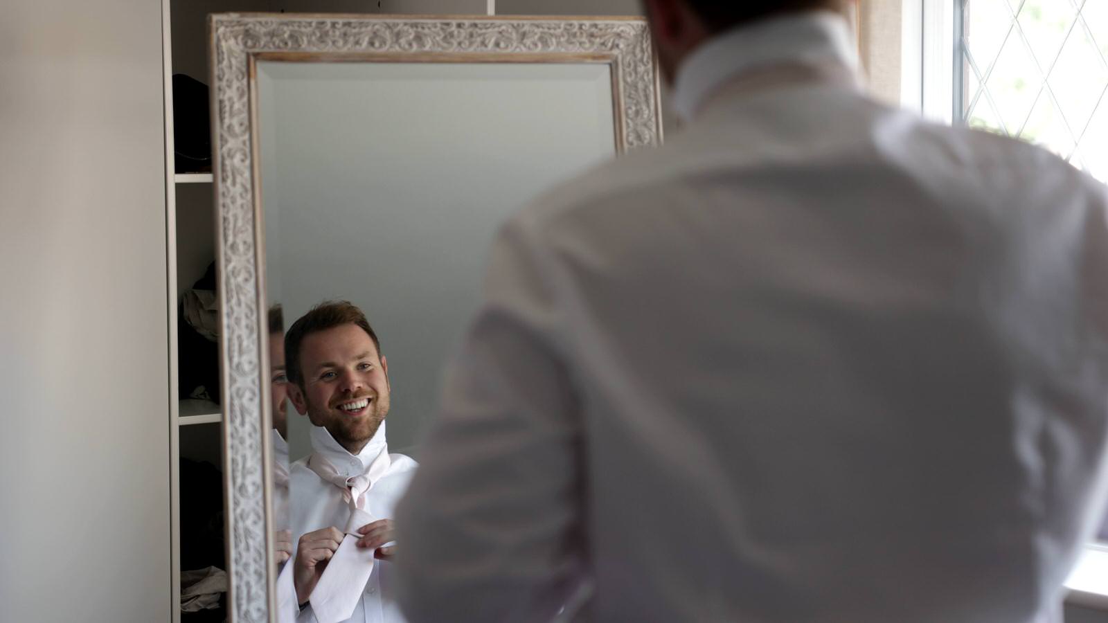 groom checks his wedding tie in the mirror