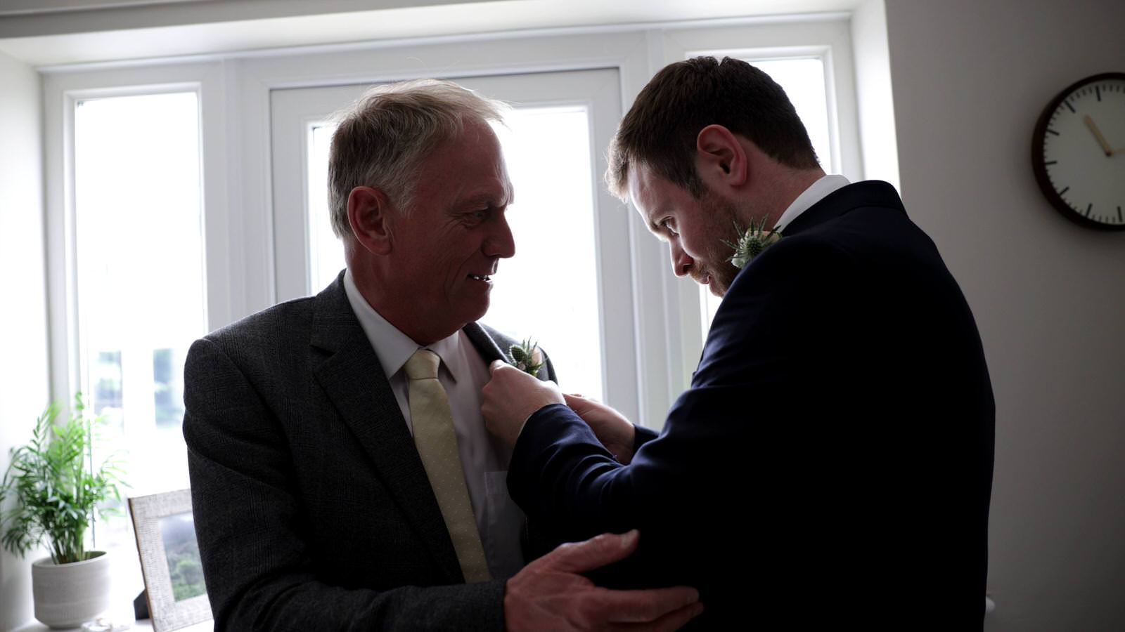 groom helps dad with buttonhole