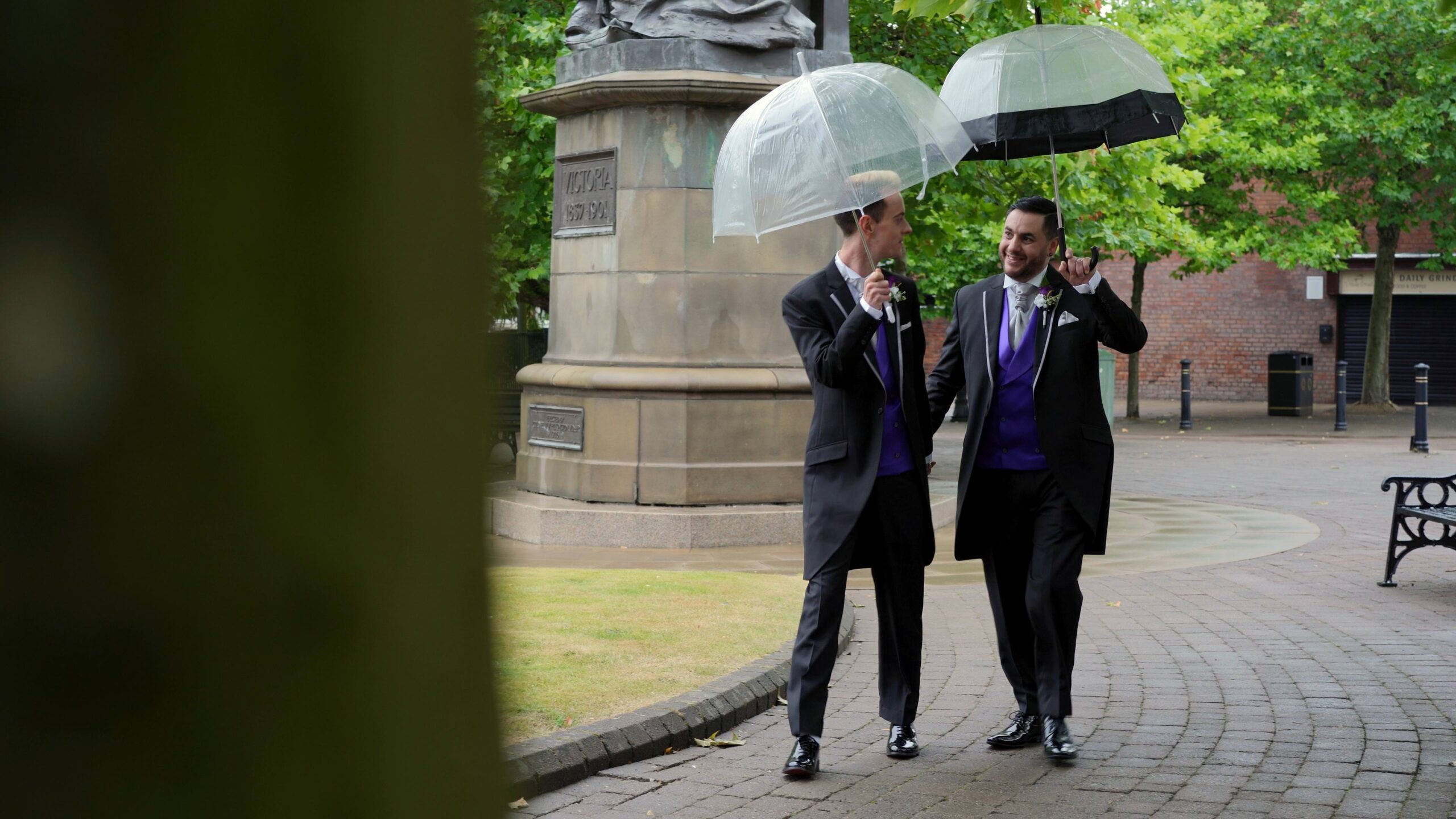 newlywed grooms walk holding umbrellas