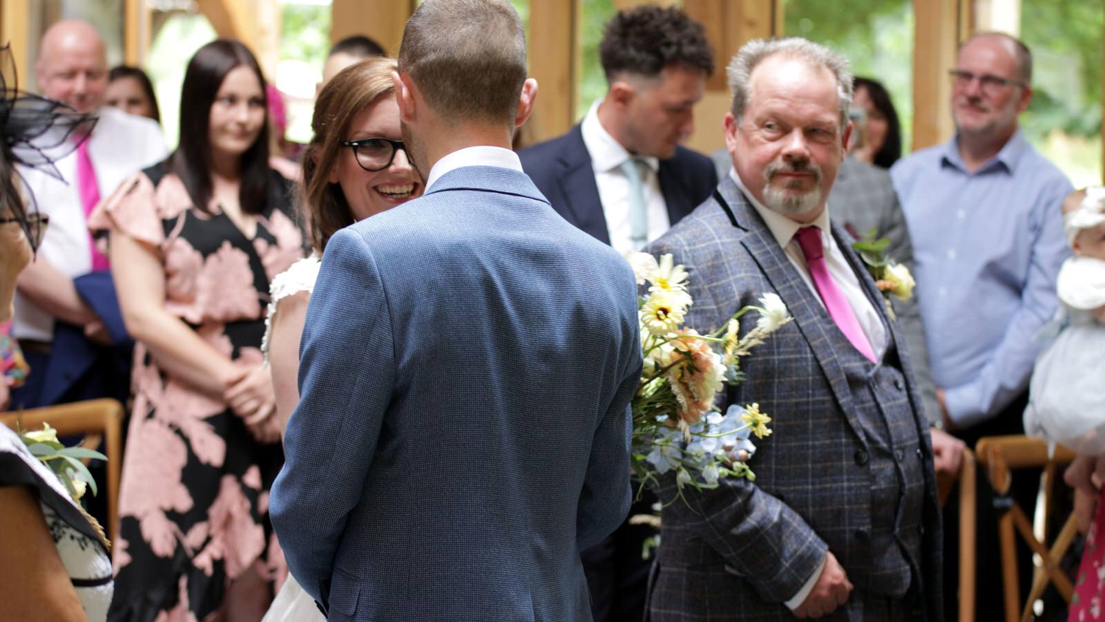 Kerry and Nicks Oaktree Peover wedding 10 bride grins at groom walking down the aisle