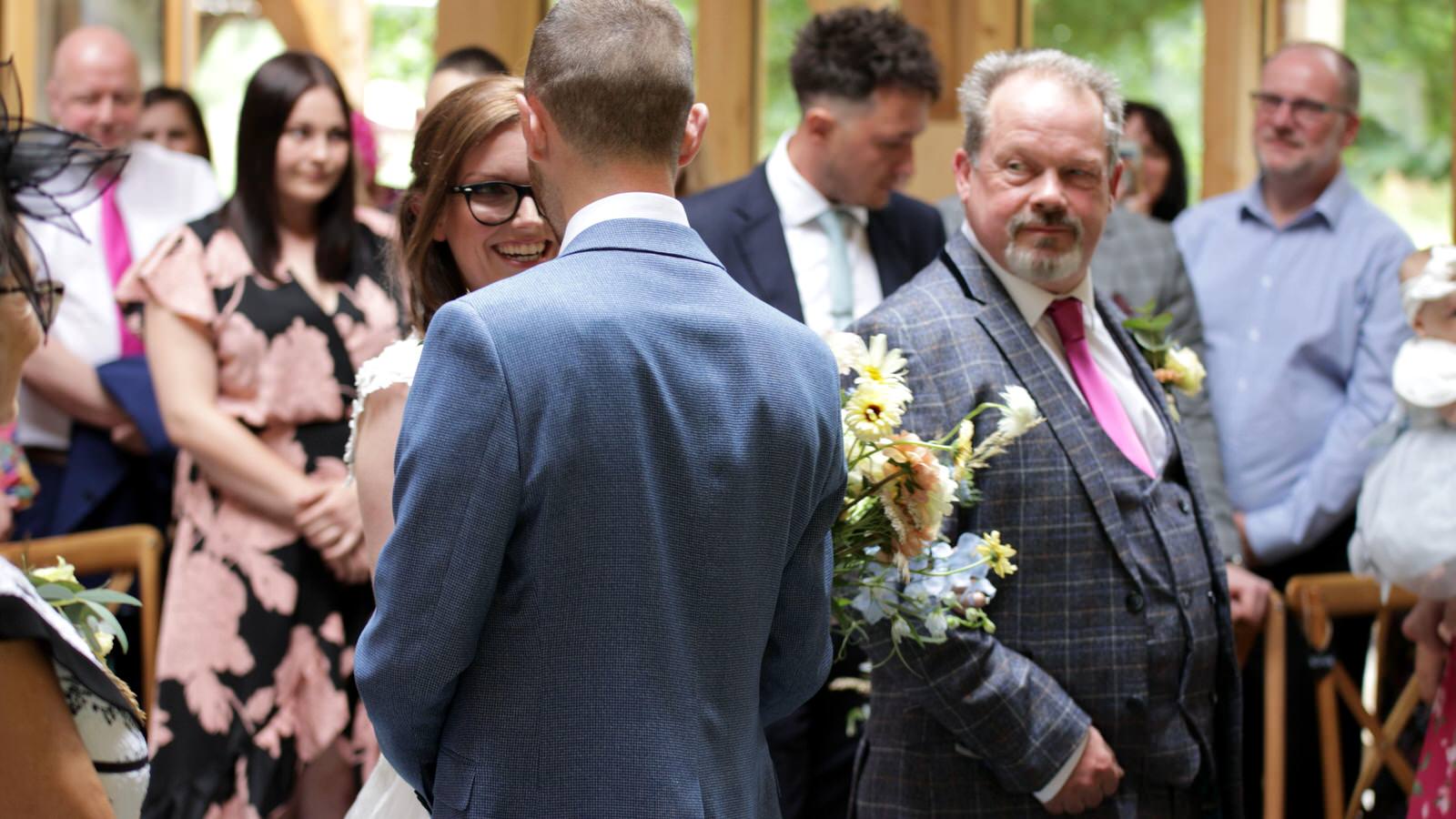 bride grins at groom walking down the aisle