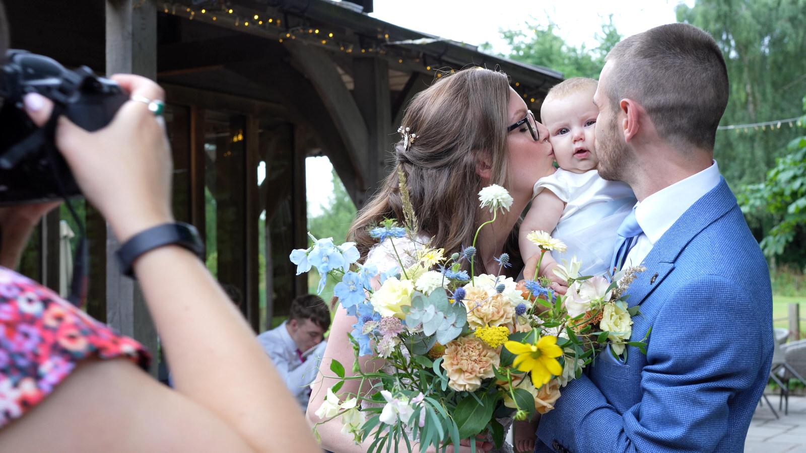 Kerry and Nicks Oaktree Peover wedding 20 photographer takes cute photo of couple kissing baby