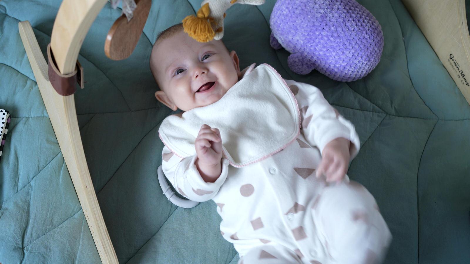 Kerry and Nicks Oaktree Peover wedding 3 smiling baby on green leaf playmat