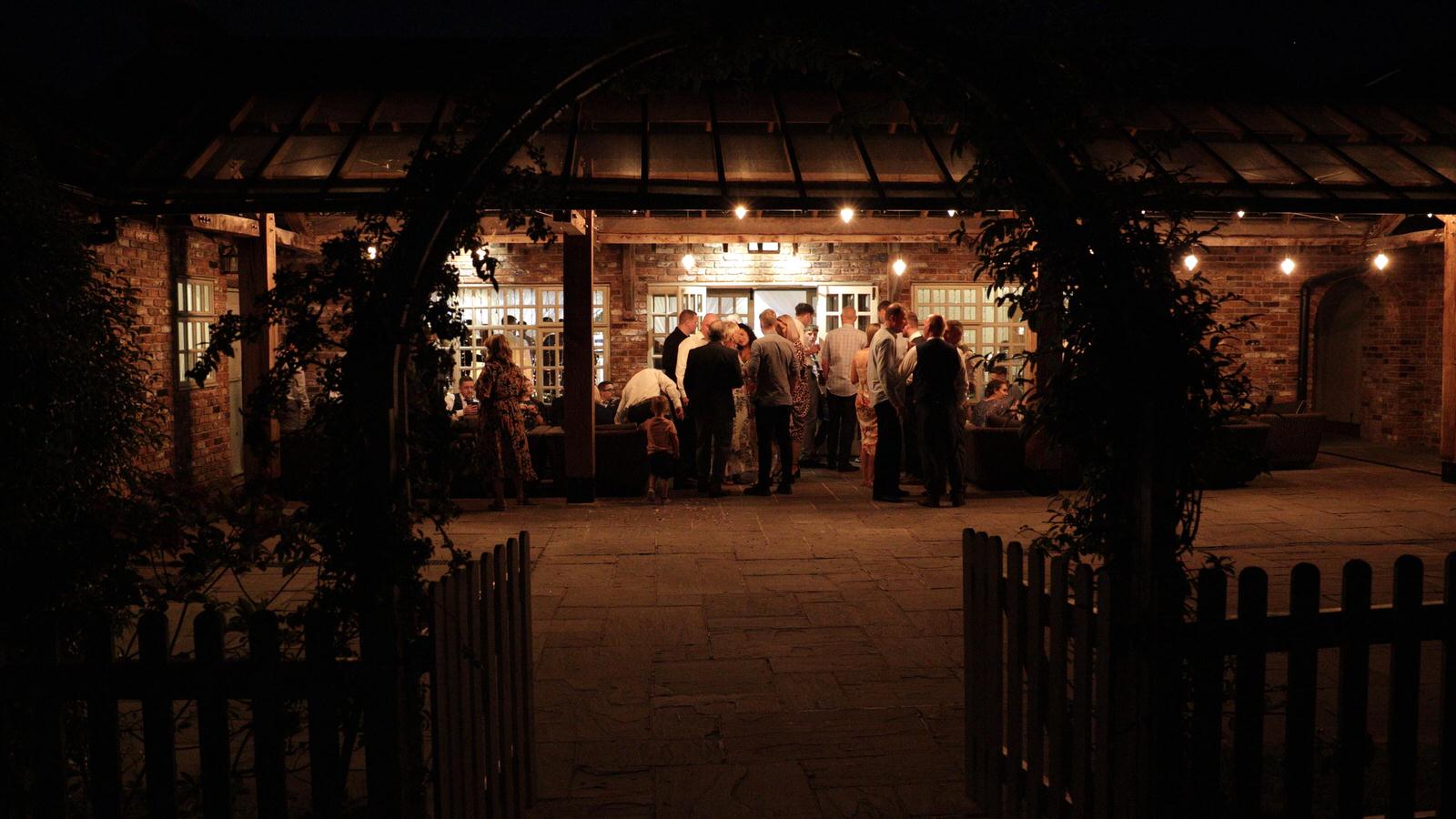 late evening shot of guests drinking outside Charnock Farm wedding