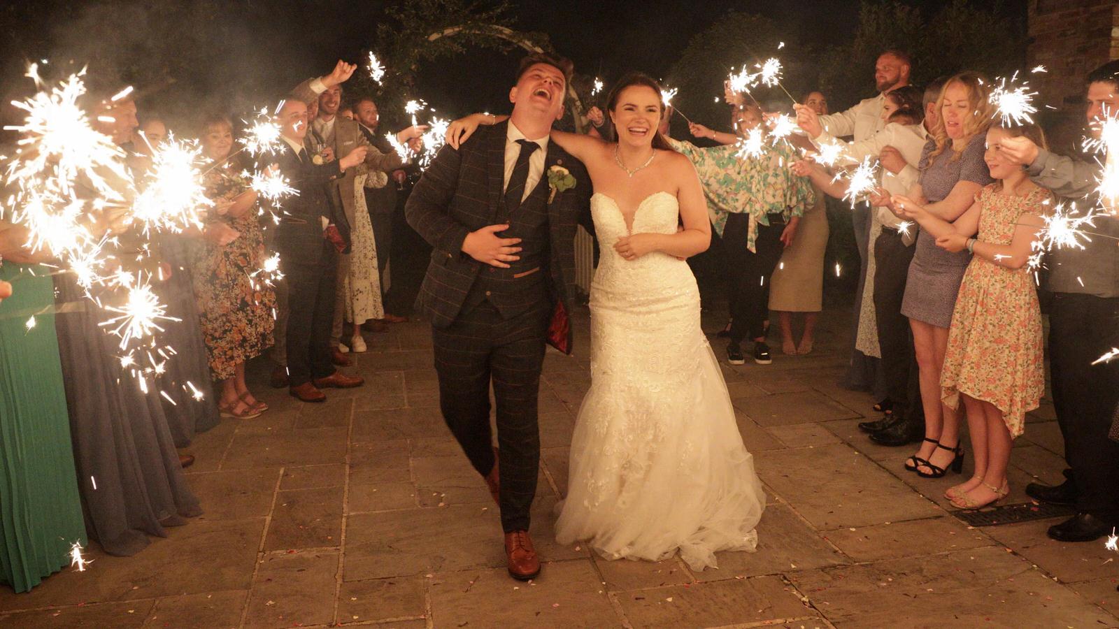 couple laugh with guests during a sparkler shot