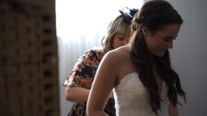 mother of the bride helps her daughter in to her dress