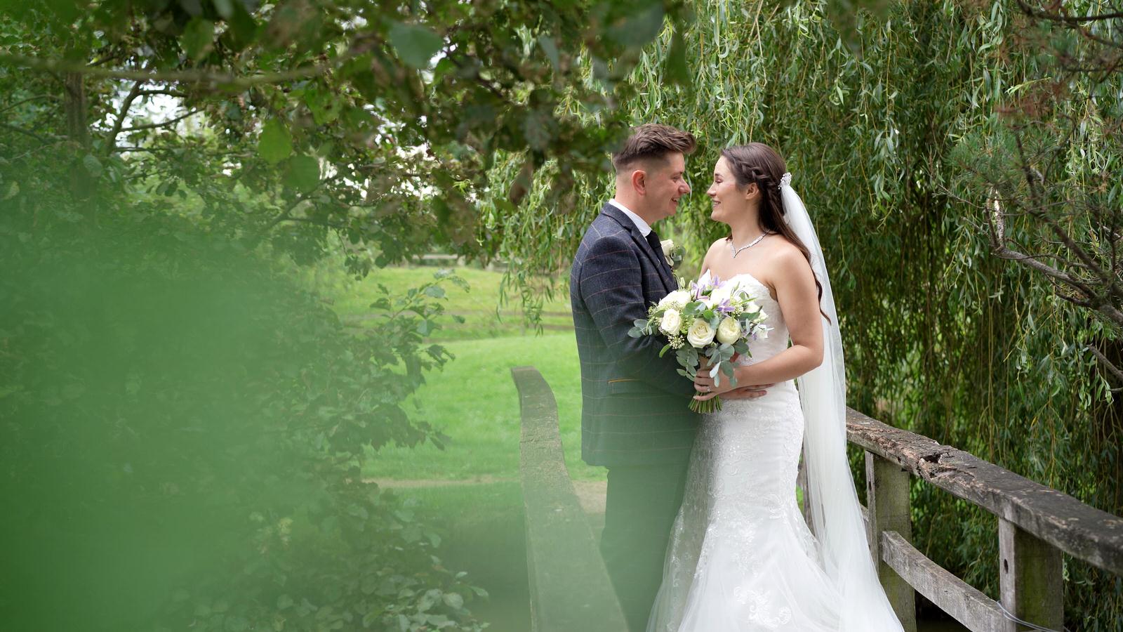 couple pose on lakeside bride at Charnock Farm