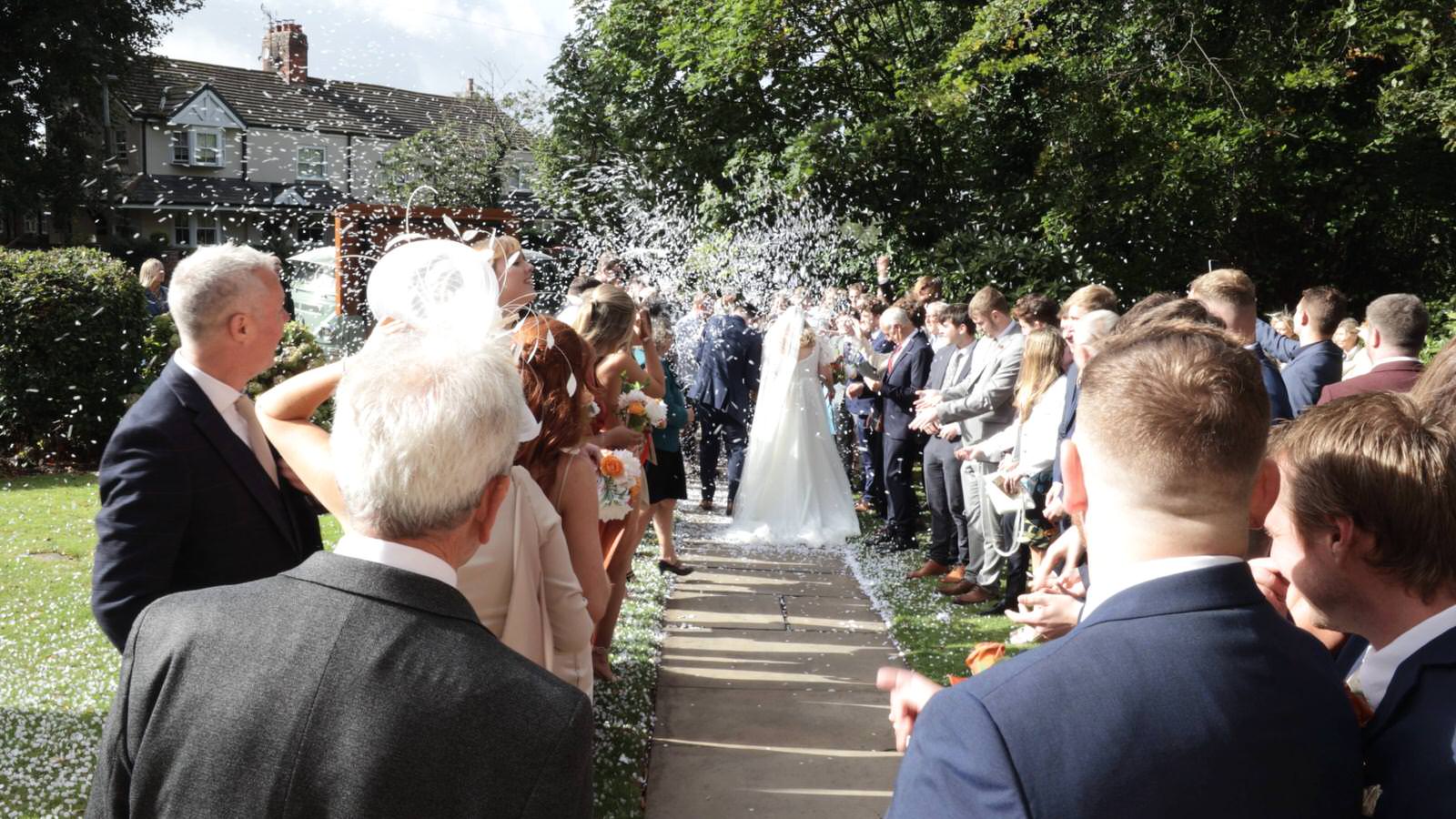 wide video shot of couple being showered in confetti