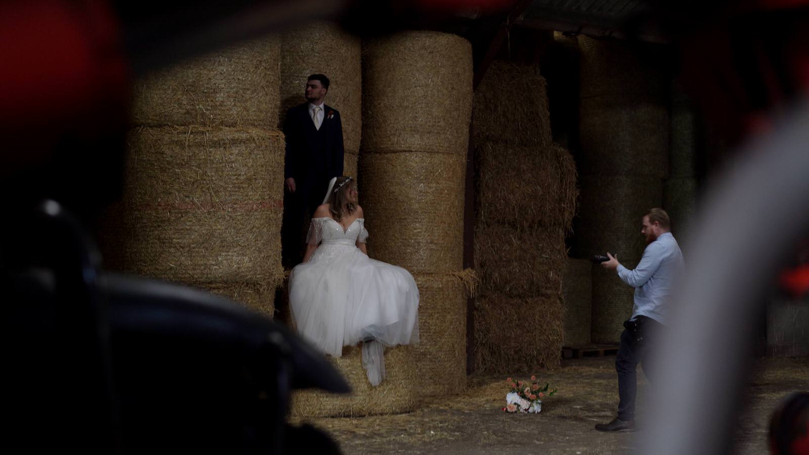 couple sit on hay bales inside barn