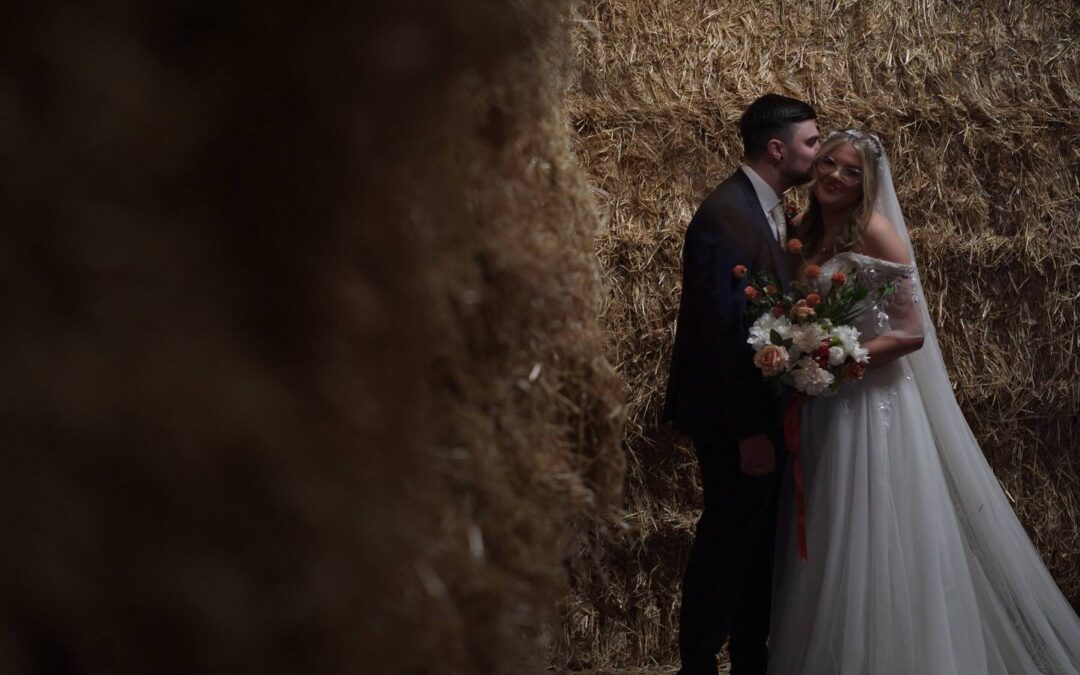 video still of couple standing by straw bales at farm wedding