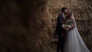 video still of couple standing by straw bales at farm wedding