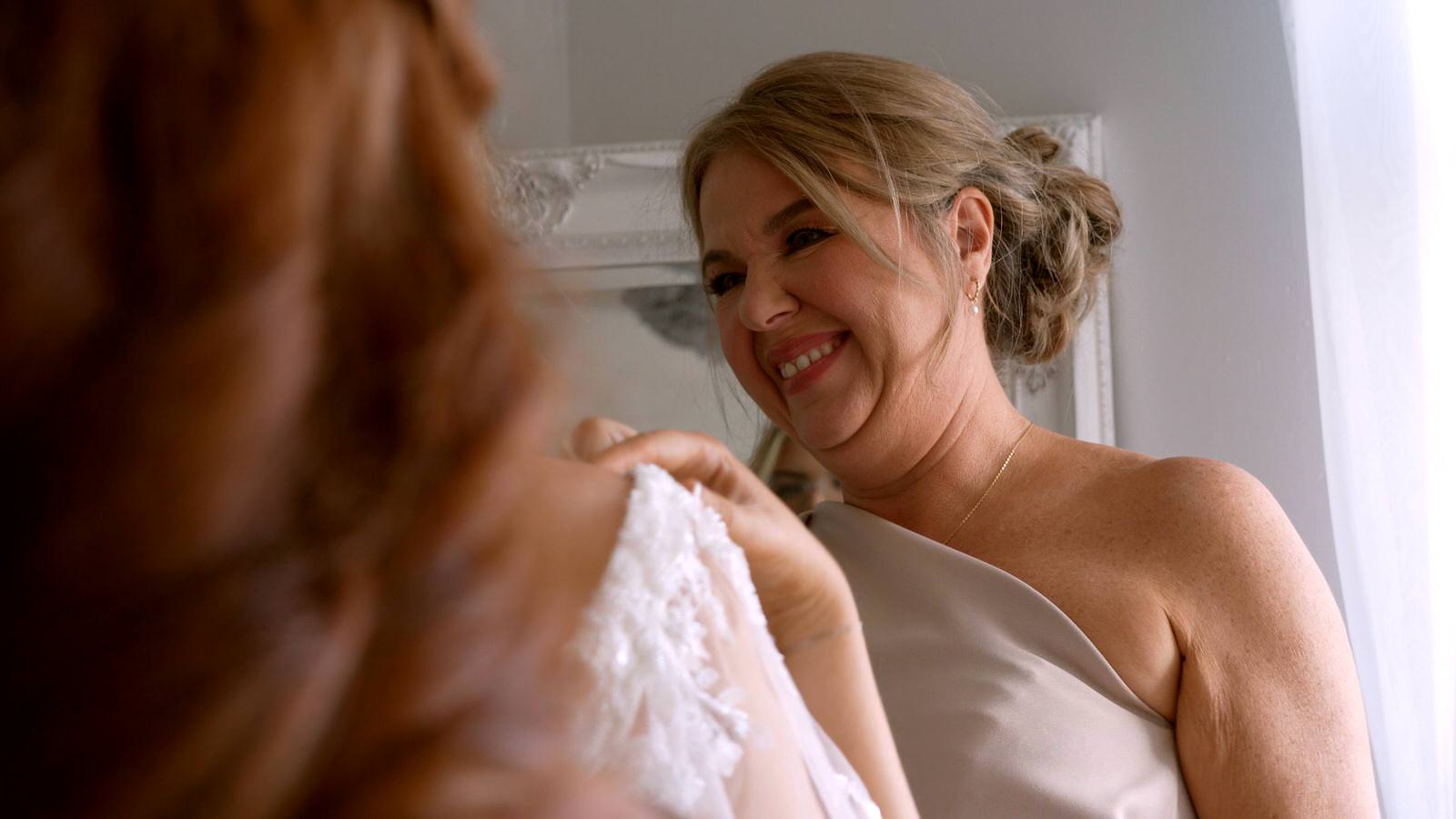 mother of the bride smiles at her daughter in her dress