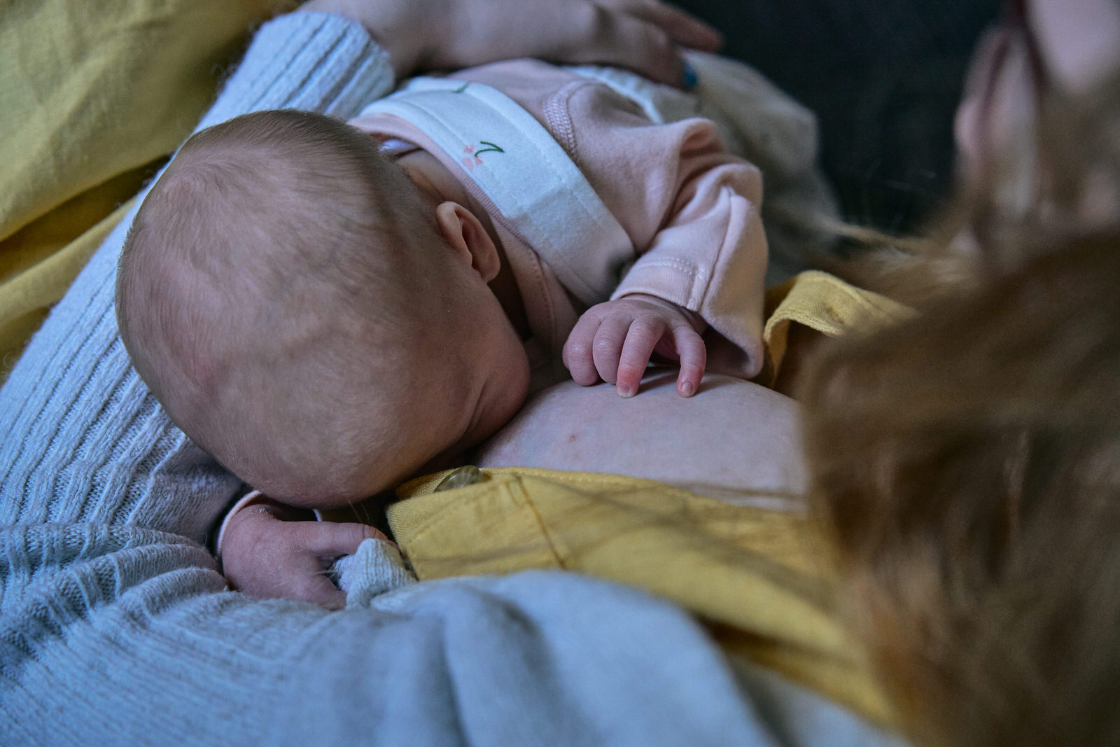 a baby breastfeeds during a photoshoot at home