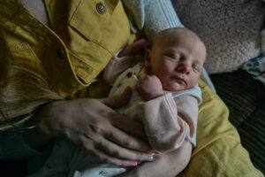 a natural light photo of a sleeping newborn in mums arms
