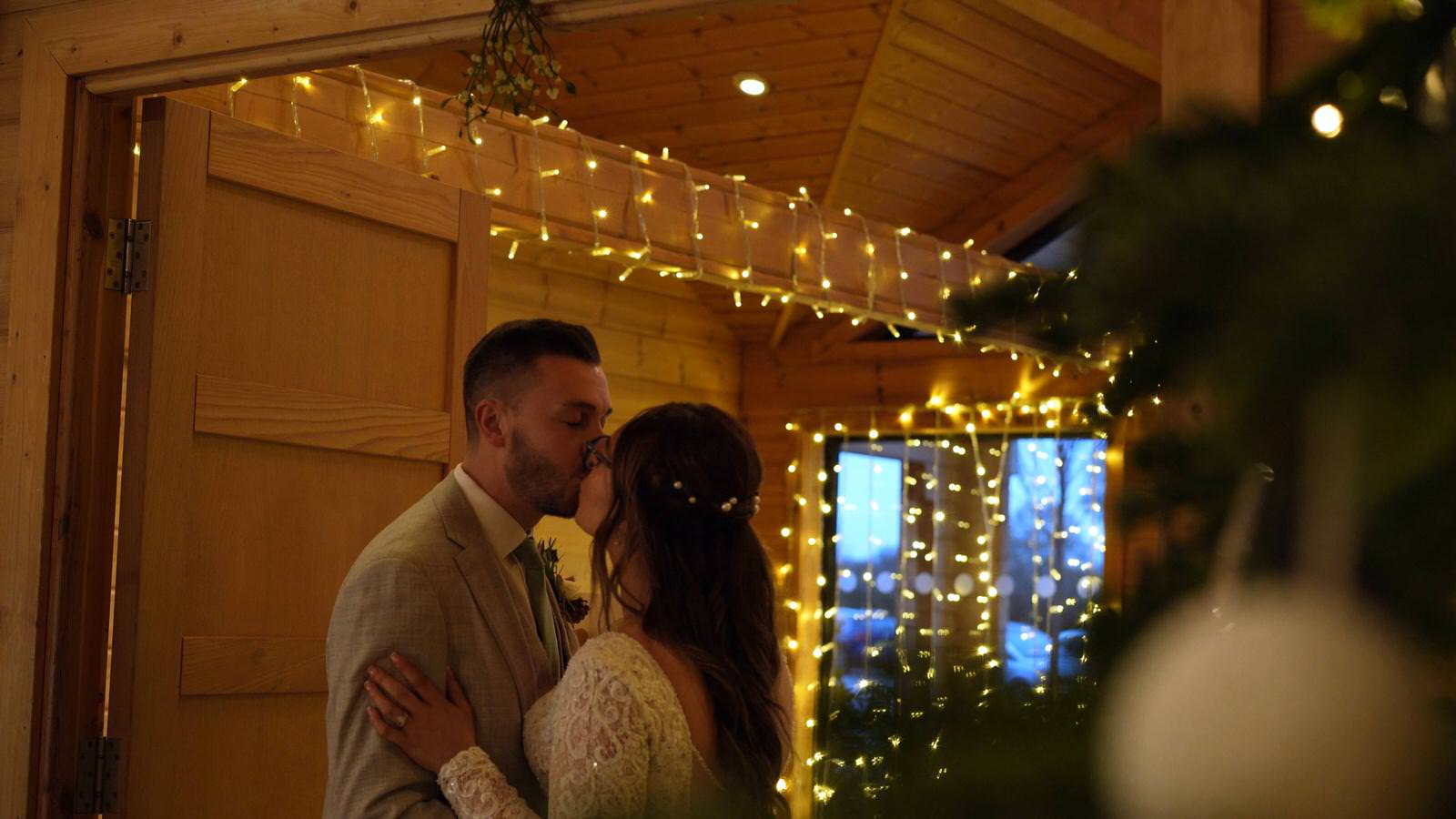 couple kiss under mistletoe during winter wedding at Styal Lodge