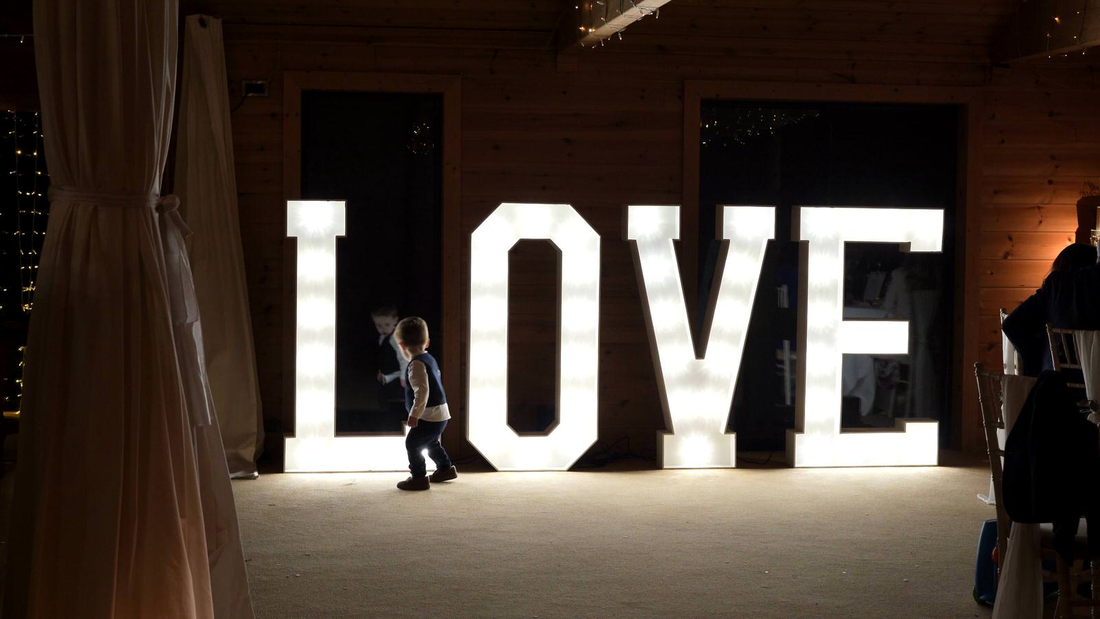 fun video still of page boy playing by light up LOVE letters