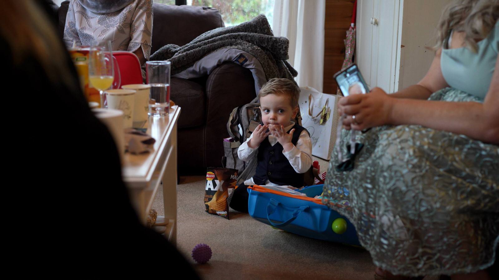 cheeky toddler pageboy sits eating snacks