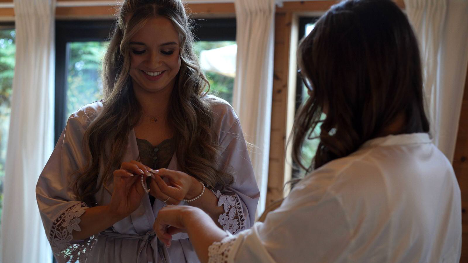 sister helps bride with her wedding jewellery