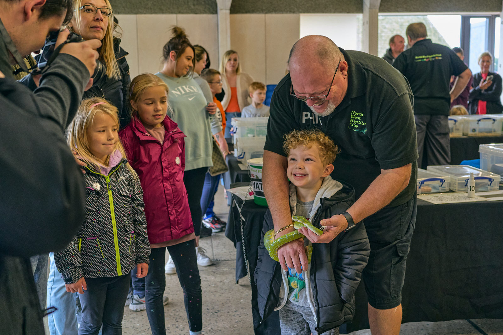 Phil the chairman of the NW Reptile club helps a child hold a snake