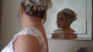 a bride looks at her reflection on the morning of her wedding