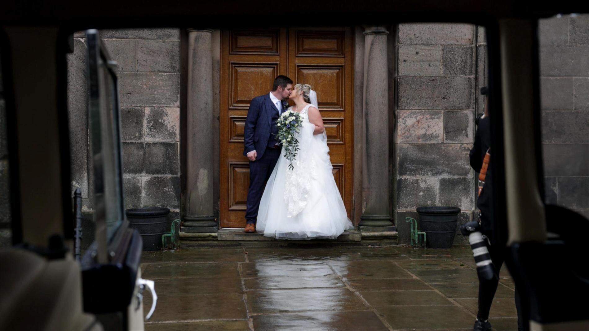 the videographer films through the wedding car window as the couple kiss outside St gregory's church
