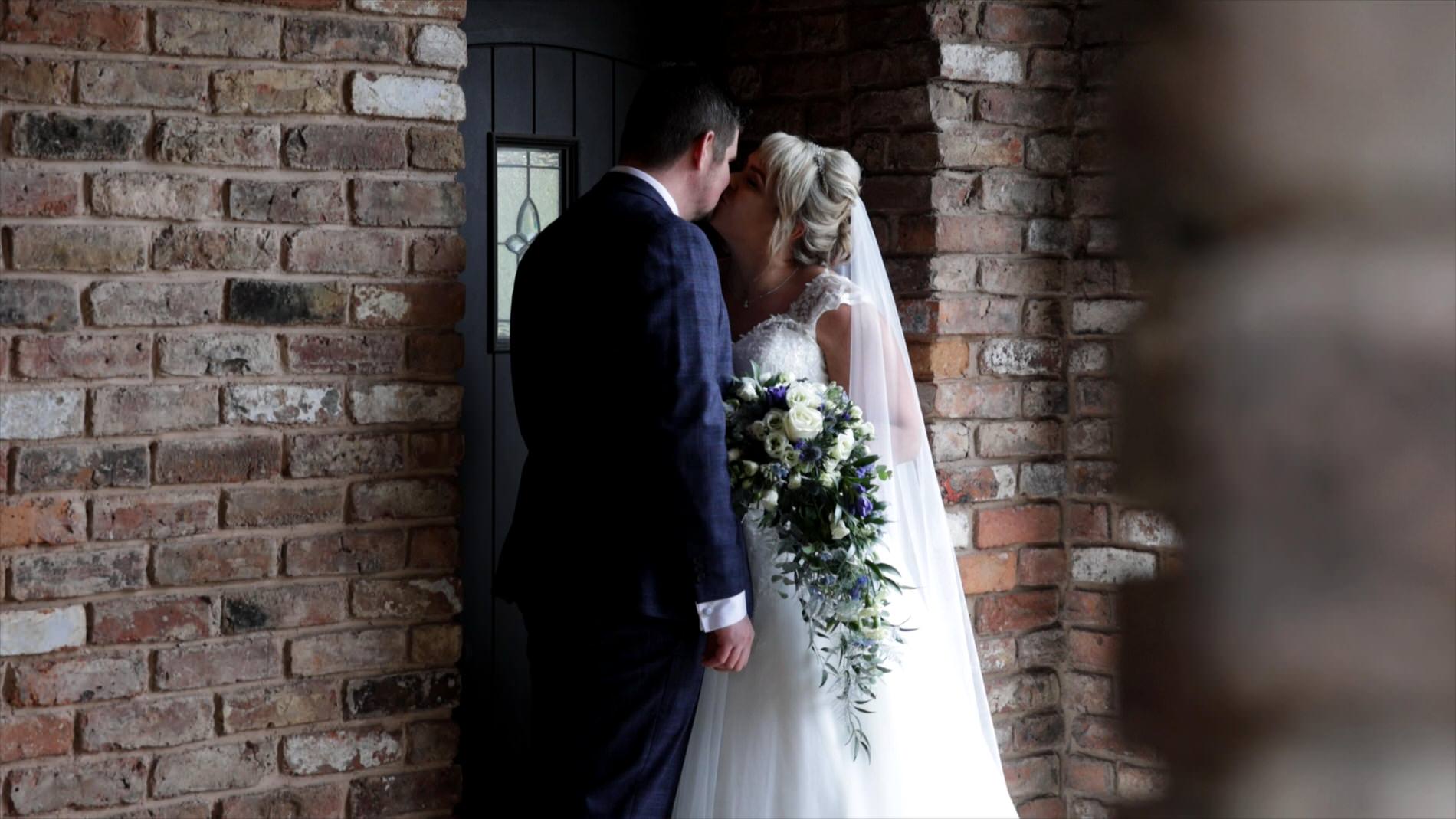 a couple pose and kiss out of the rain at Charnock Farm