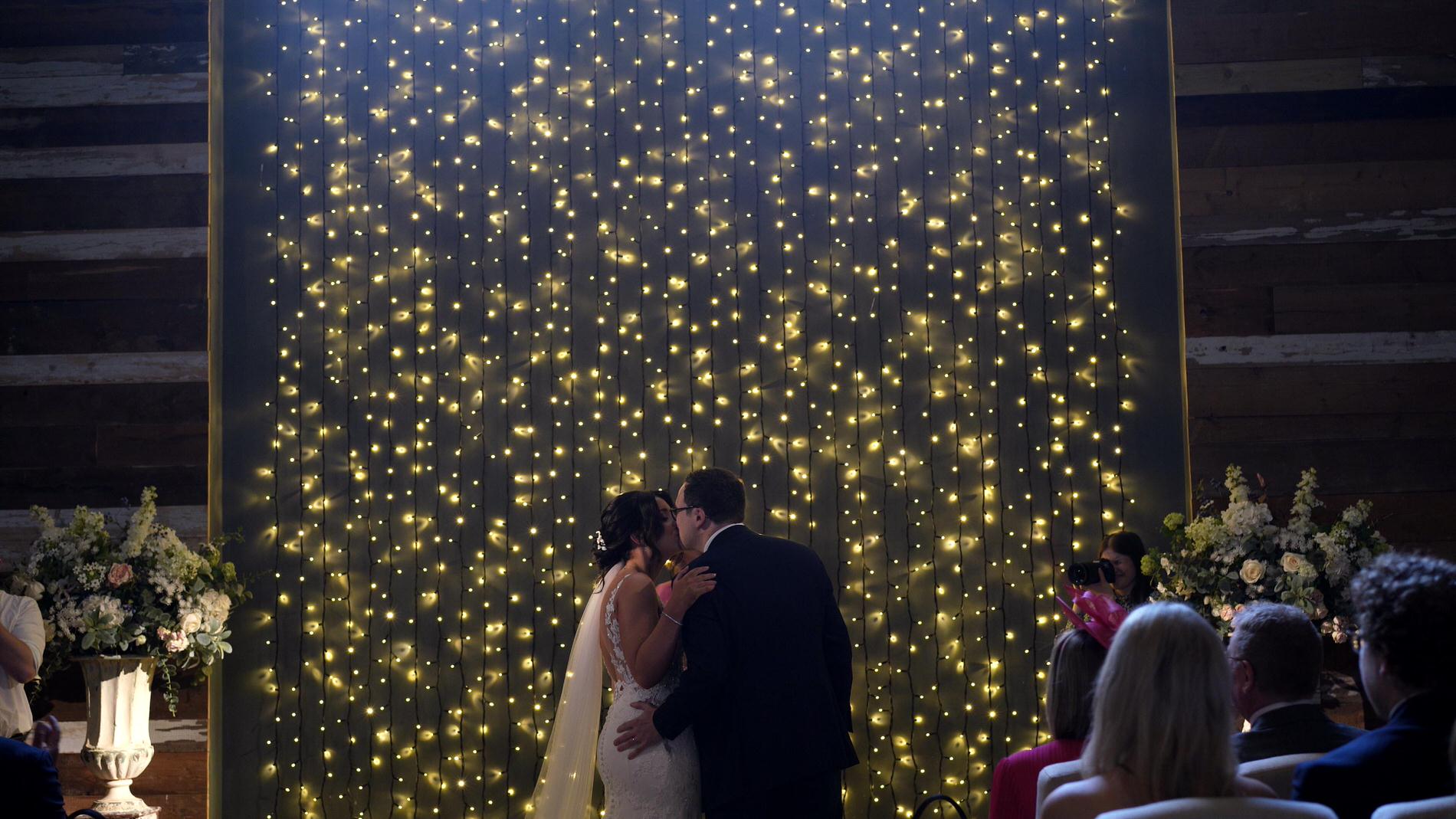 a couple kiss in front of the fairy lights at Wharfdale Grange in Yorkshire
