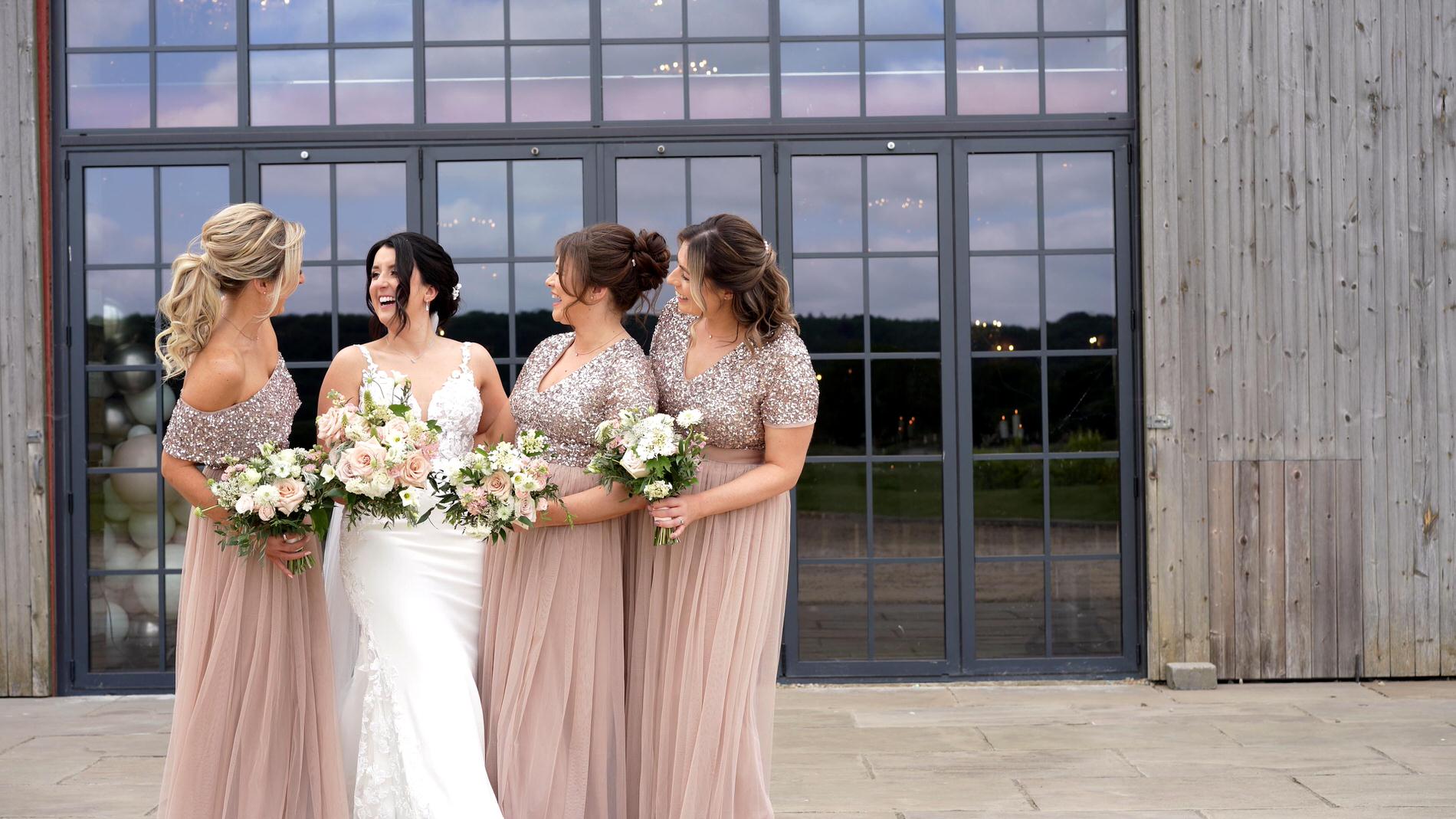 the bride laughs with her bridesmaids for the photographer and videographer