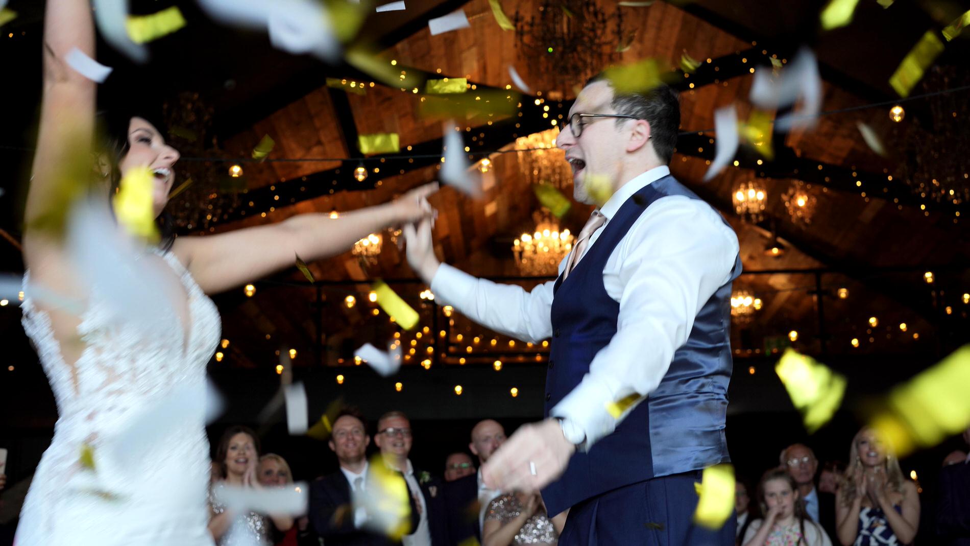 the couple dance with their arms in the air as confetti falls
