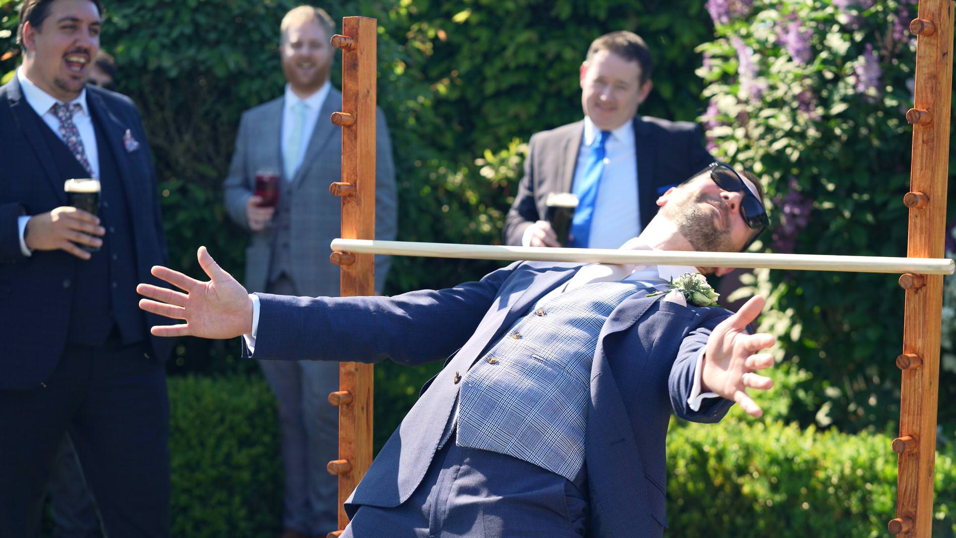 Groom tries to limbo during wedding reception at Pryors Hayes Golf Club