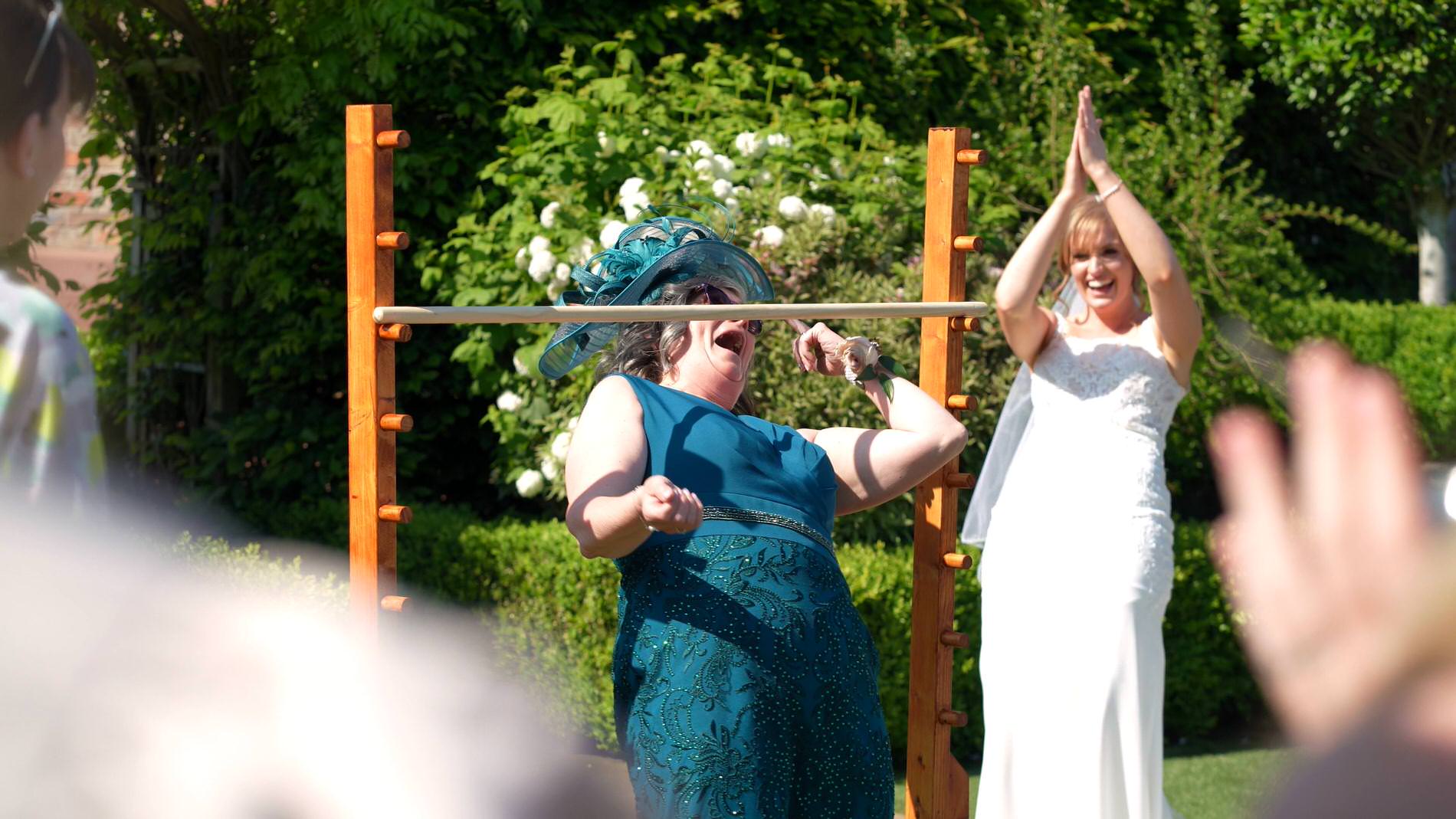 mother of the bride tries t limbo with a big fascinator on