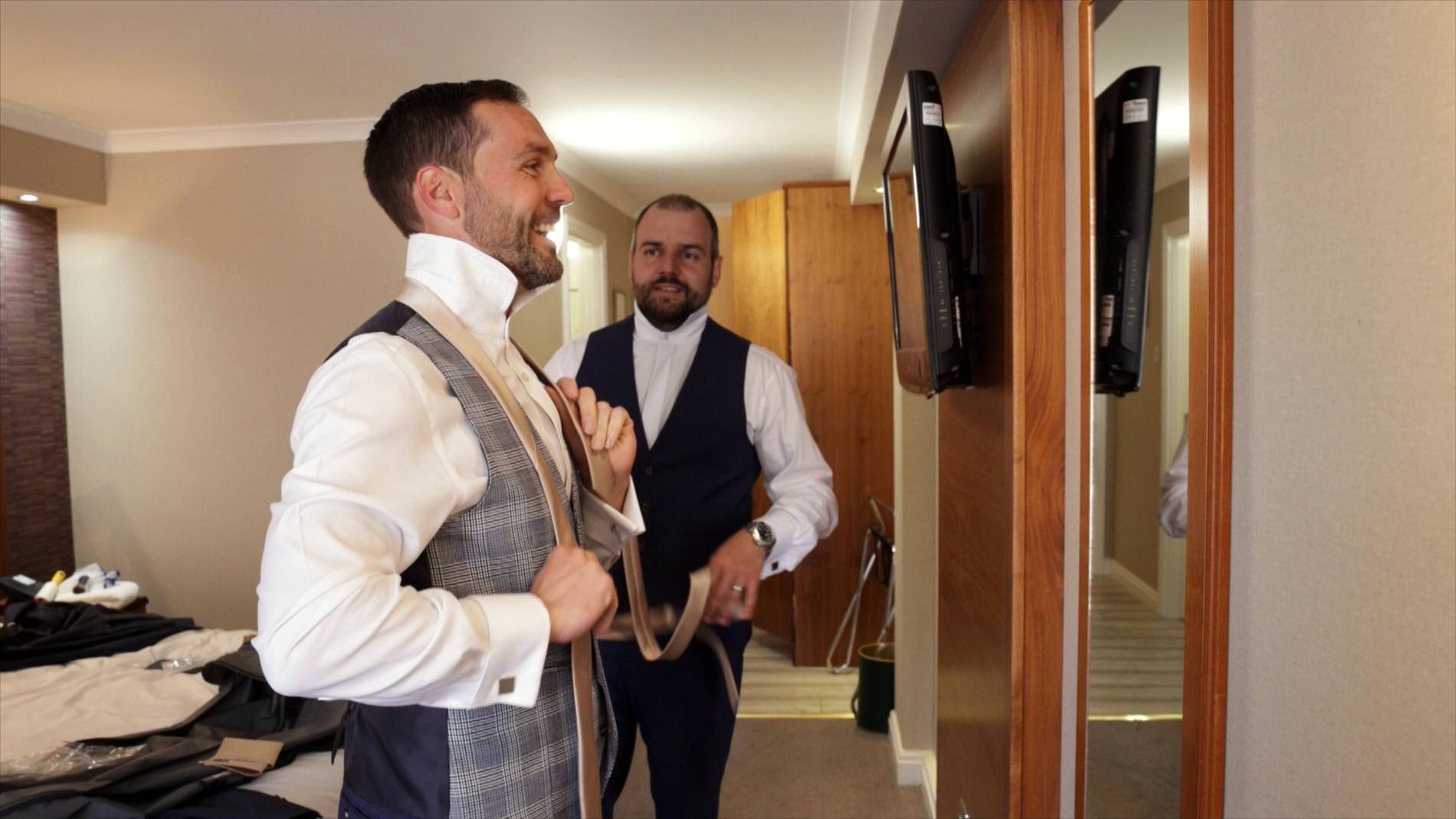 groom looks in the mirror to do his tie