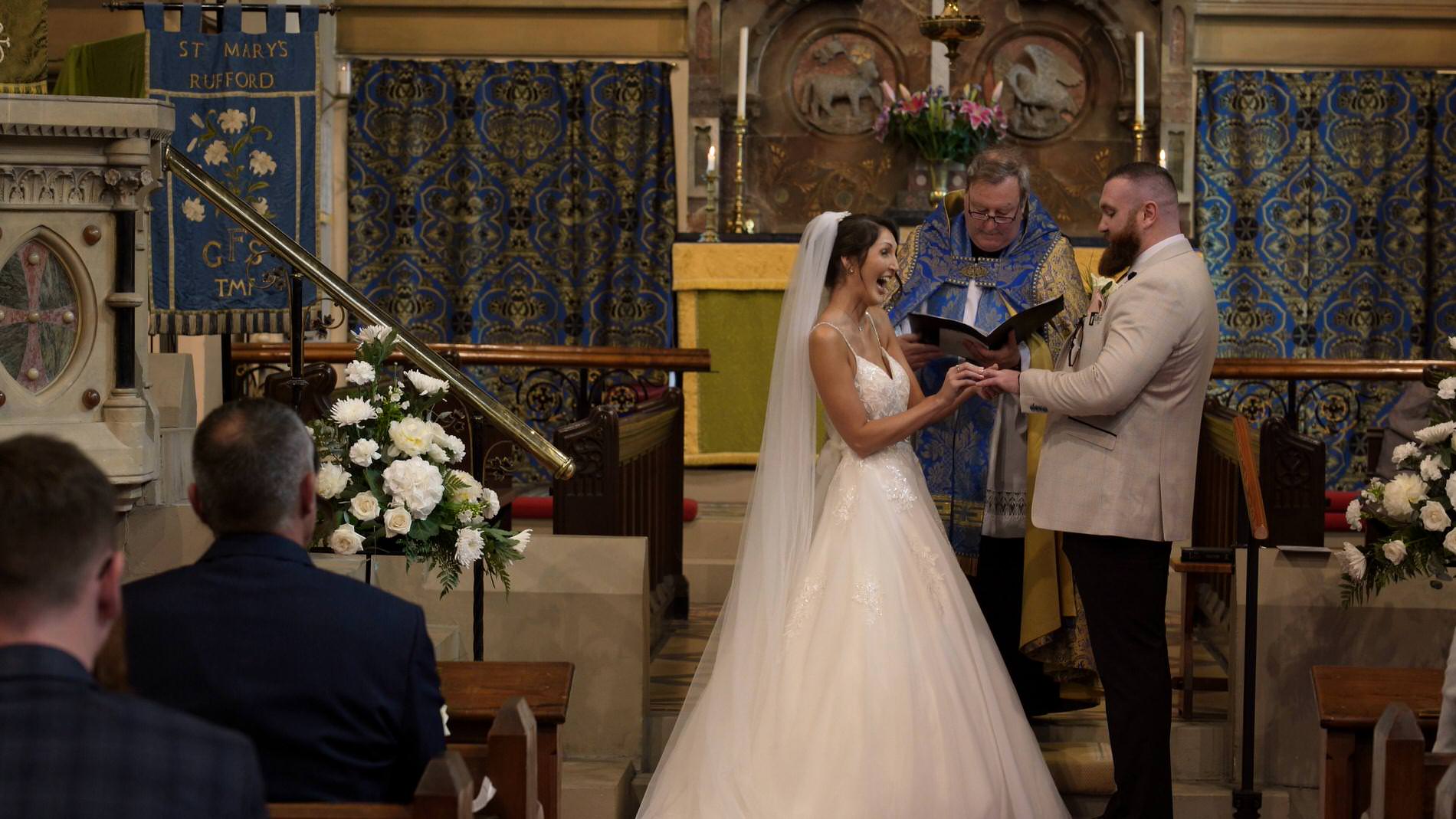 the bride places the wedding ring on the grooms hand