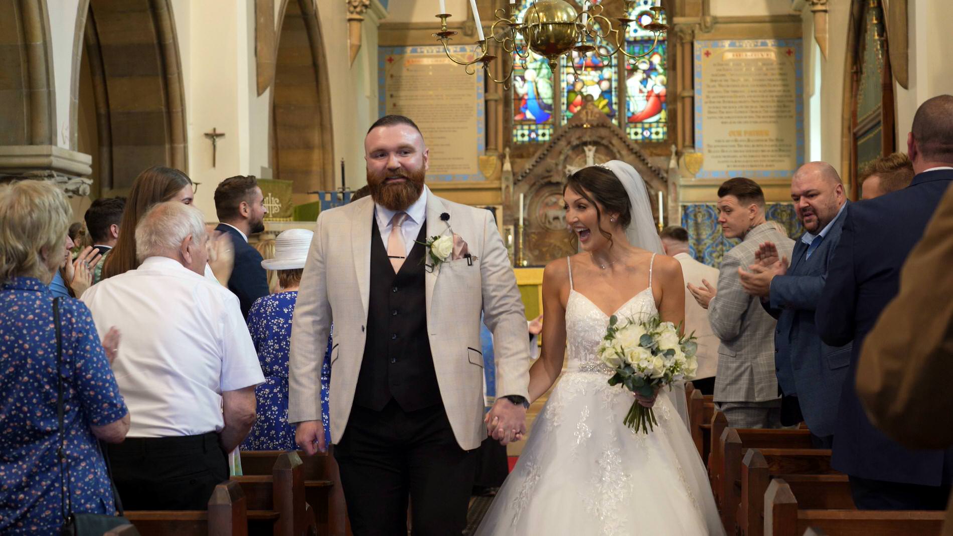 a couple walk down the aisle after a church ceremony