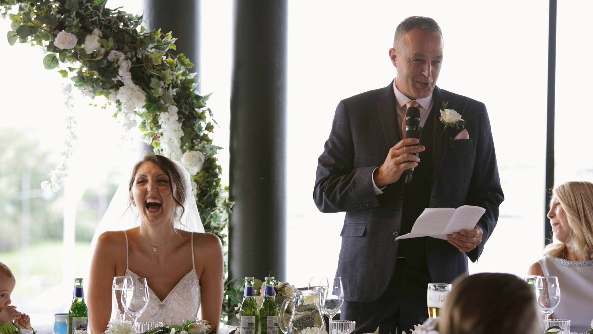 the father of the bride makes his daughter laugh during speeches at The Waterfront Southport