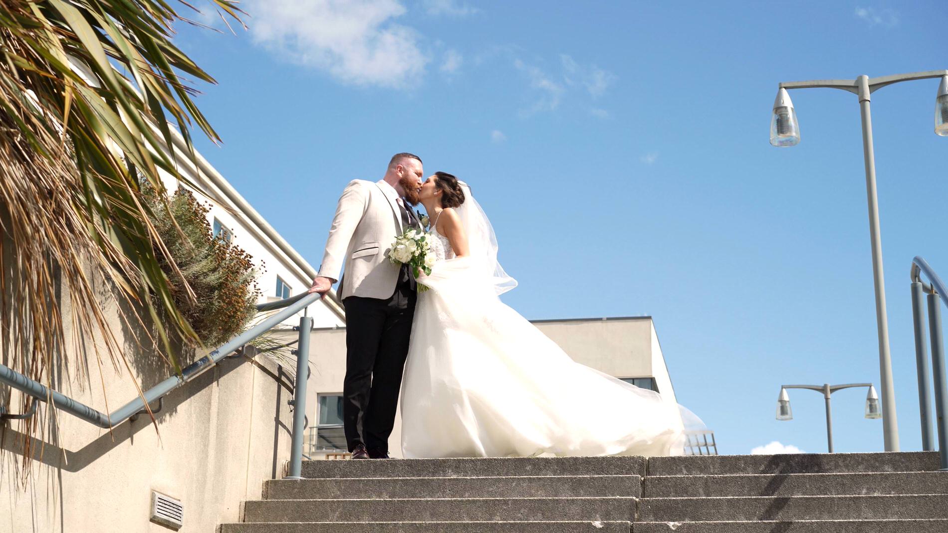 the couple kiss on the steps down to the marina at The Waterfront Southport