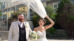 the videographer captures the brides veil trying to blow away in the sea breeze