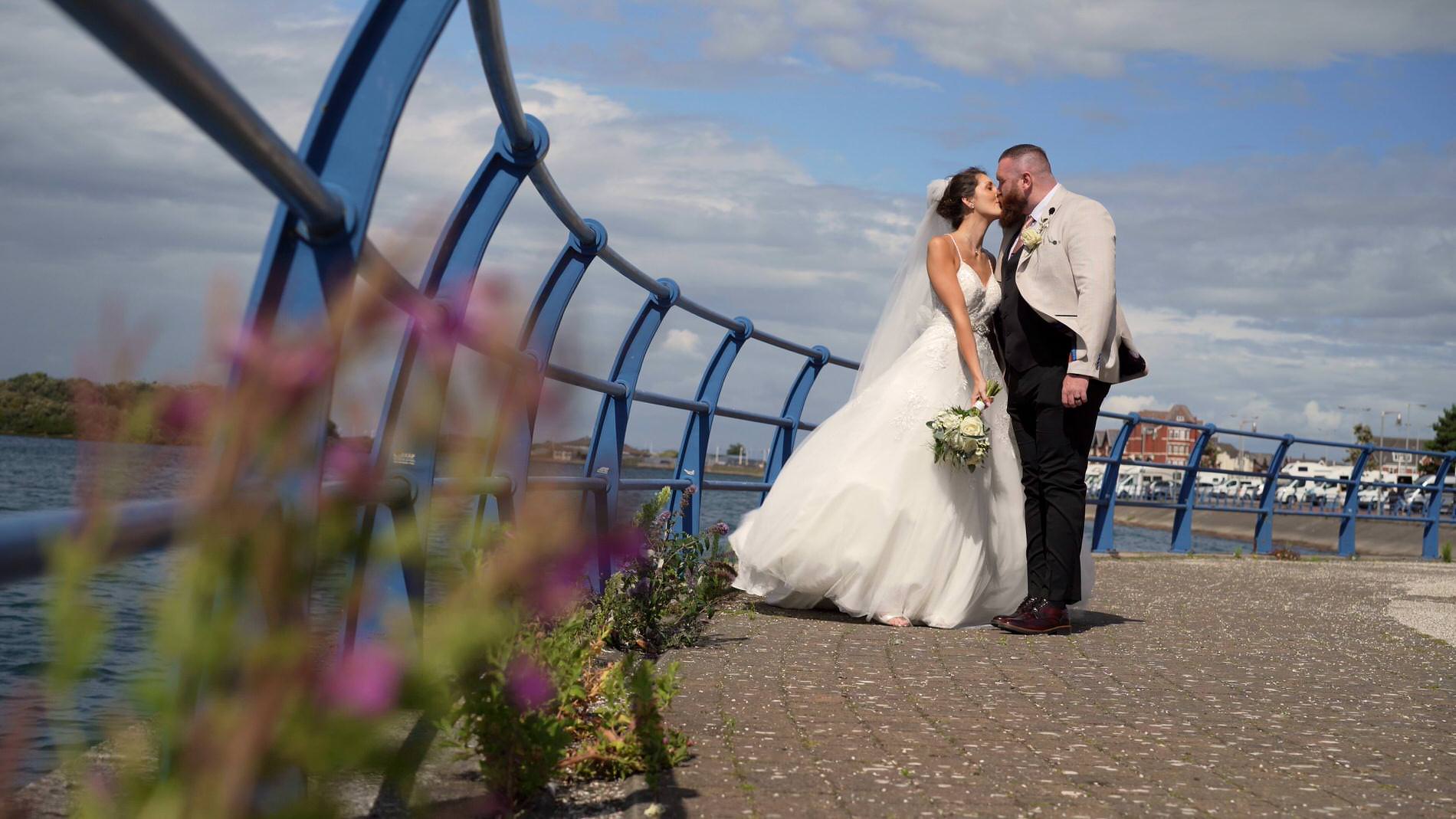 a bride and groom kiss on the edge of Southport Marina