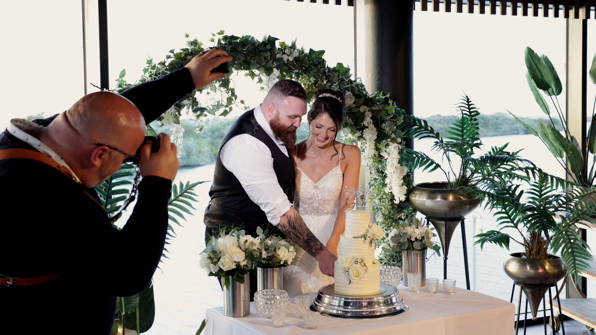 the couple cut their cake for the photographer and videographer at The Waterfront Southport