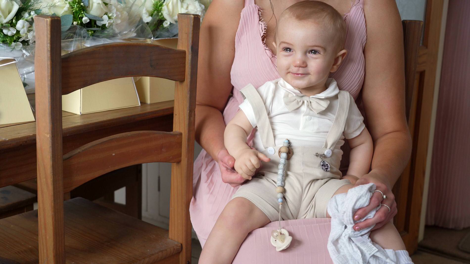 a page boy smiles as he's dressed in his linen romper