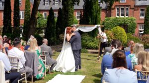 the couple kiss during an outdoor wedding ceremony at Nunsmere hall