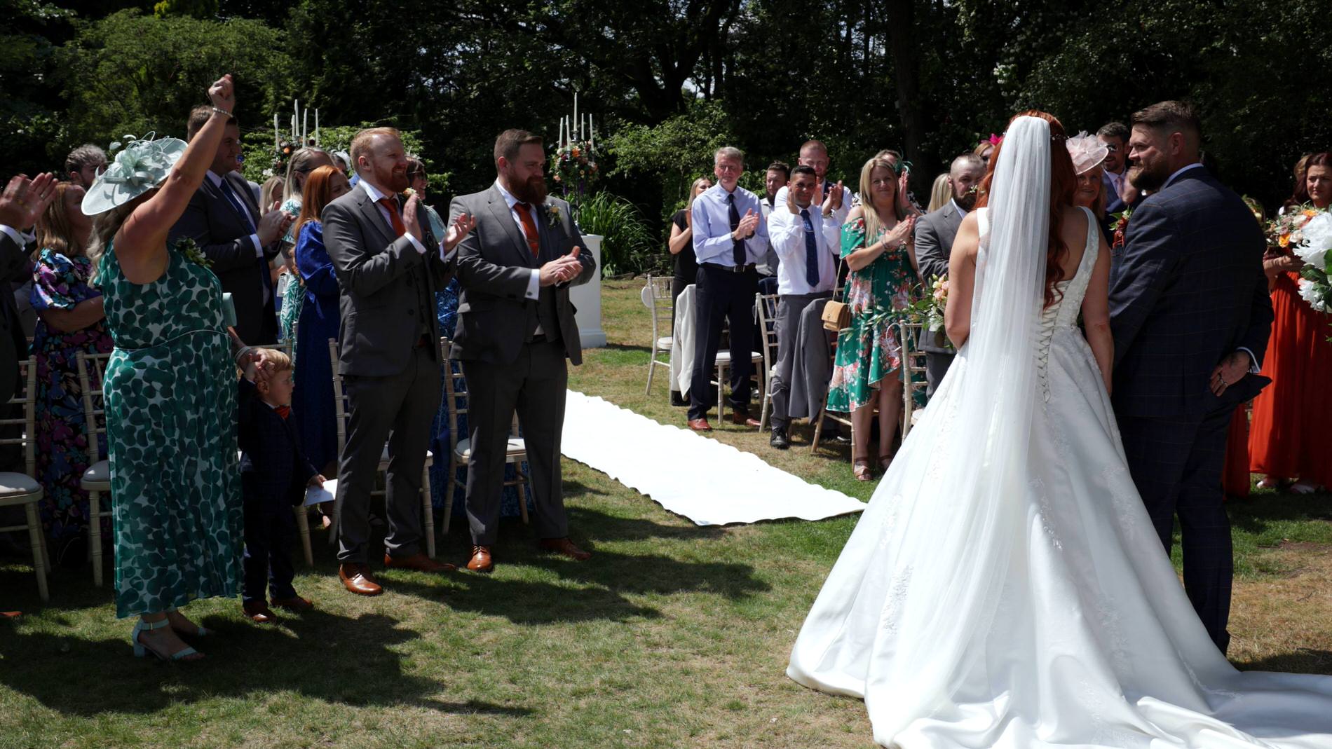 guests cheer as the couple walk down the aisle at Nunsmere hall