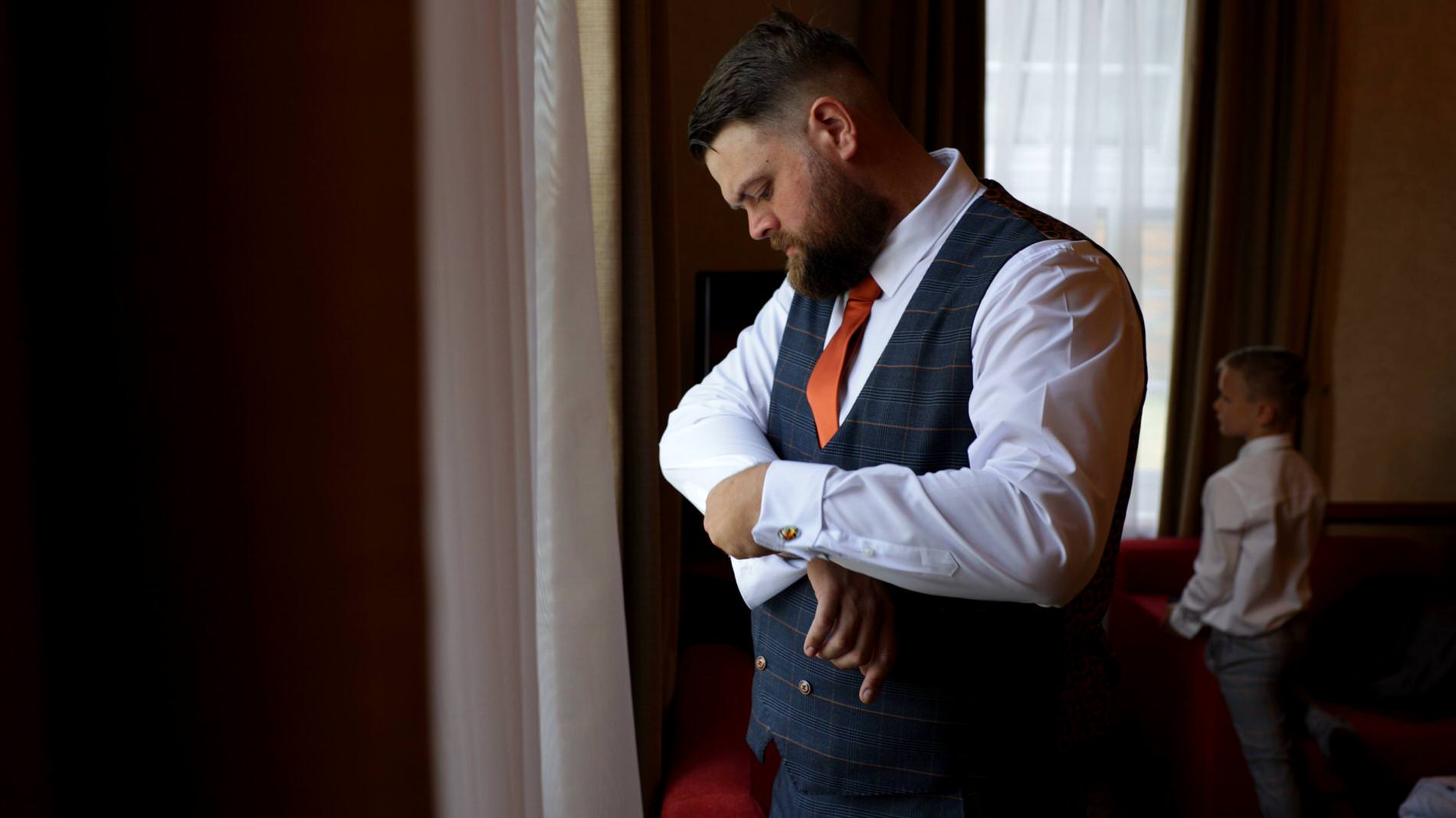 groom fastens his cufflinks before wedding