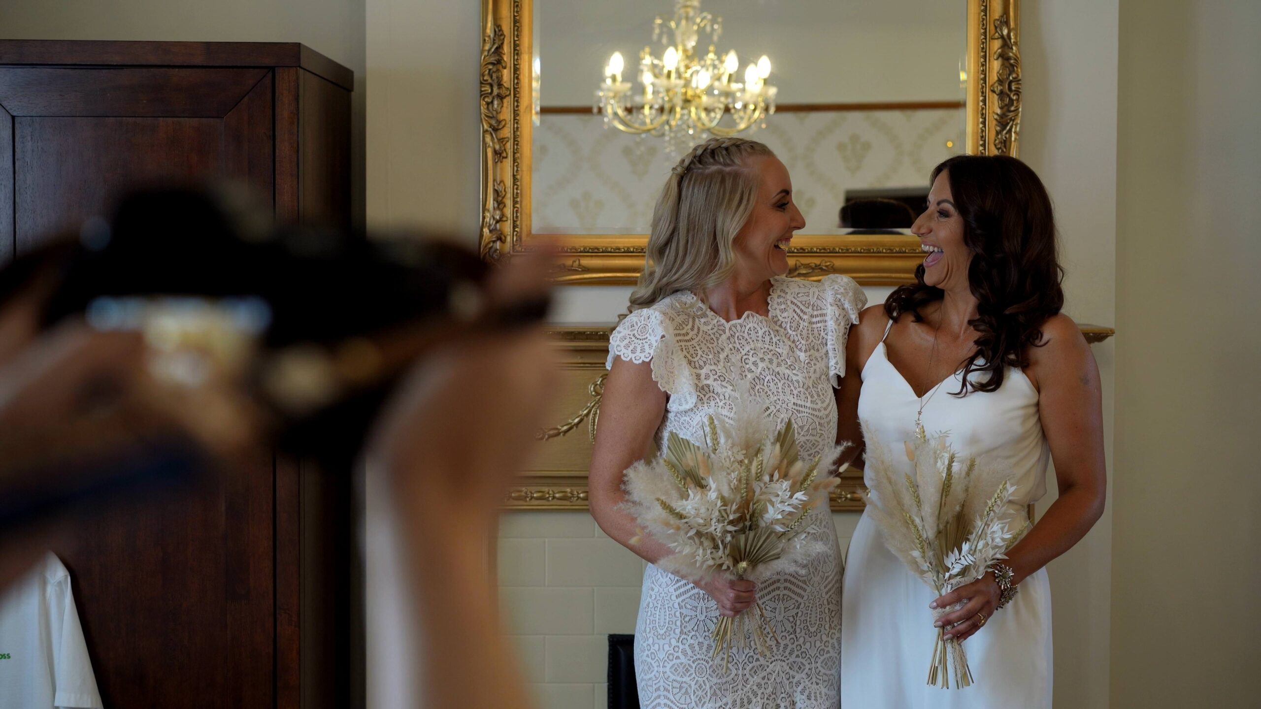 the bride and maid of honour laugh for the photographer and videographer