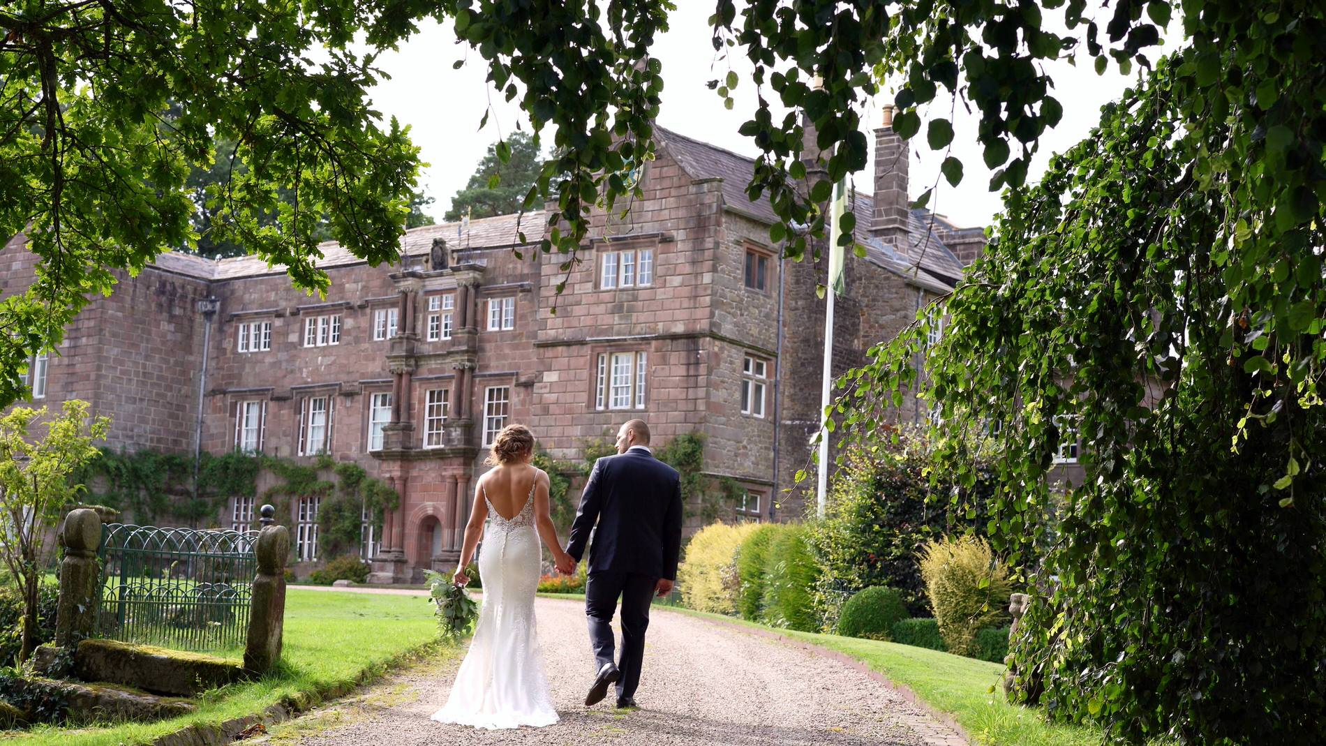 the couple walk through the gardens at Browsholme Hall in lancashire