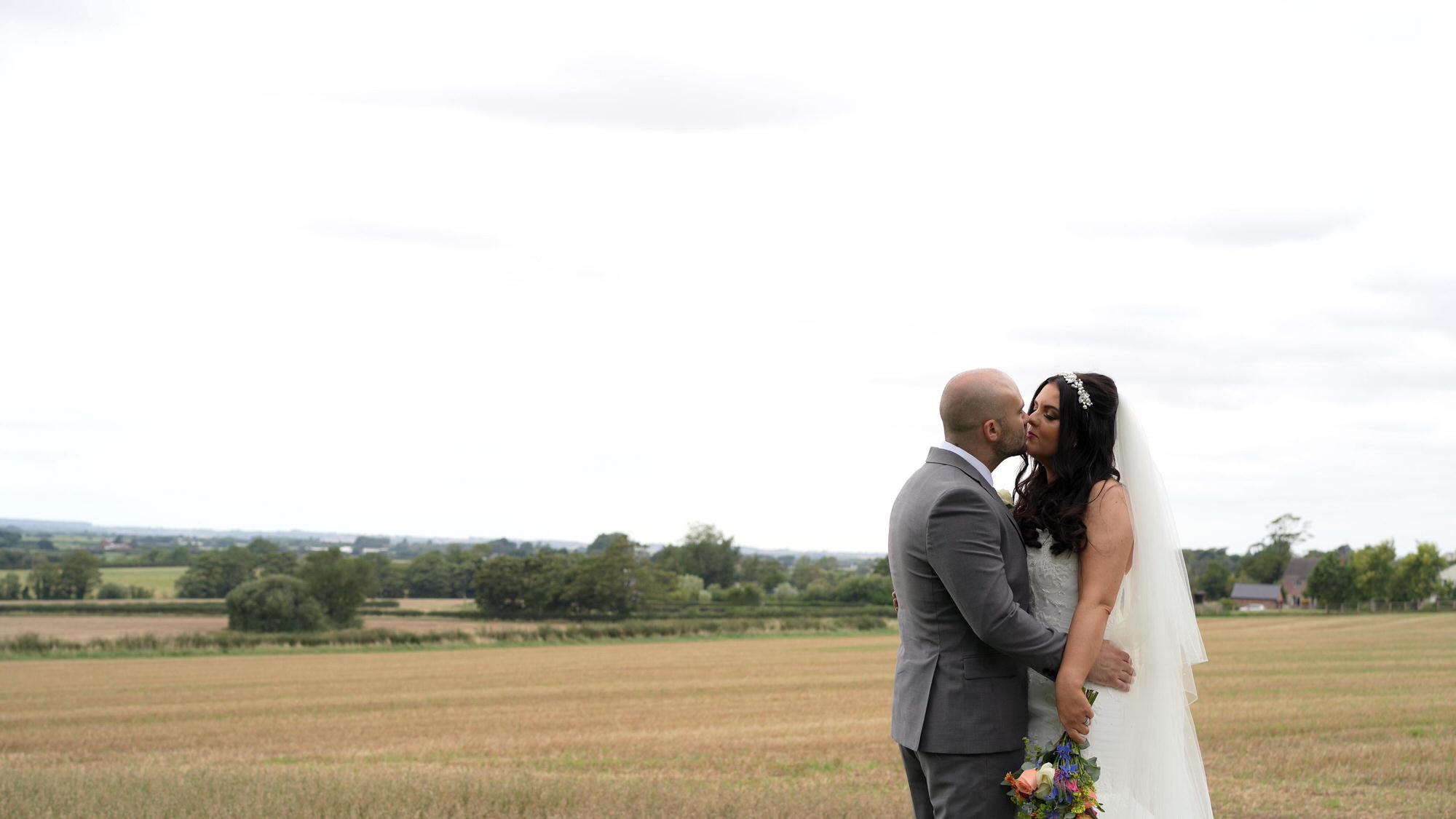a couple kiss at the edge of a farmers field outside West Tower