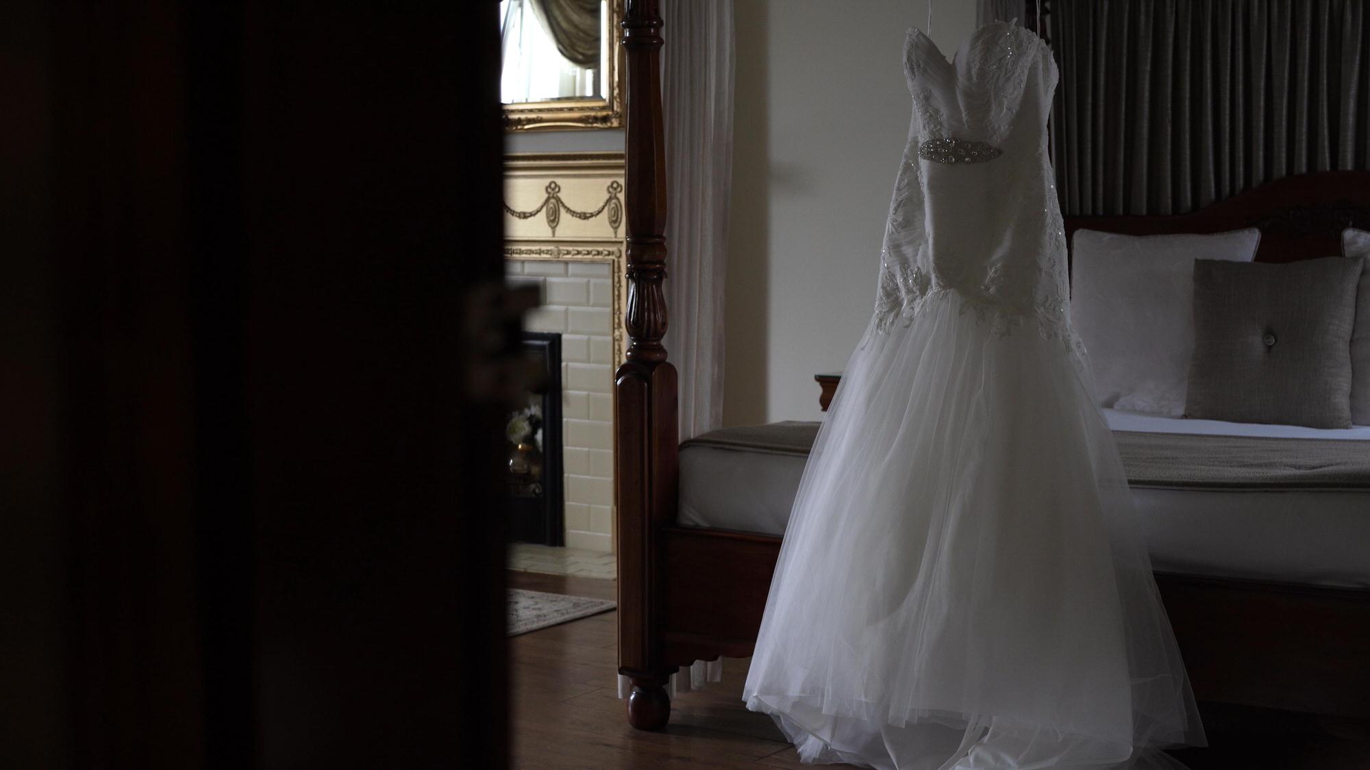 a wedding dress hangs on the four poster bed in West Towers bridal suite