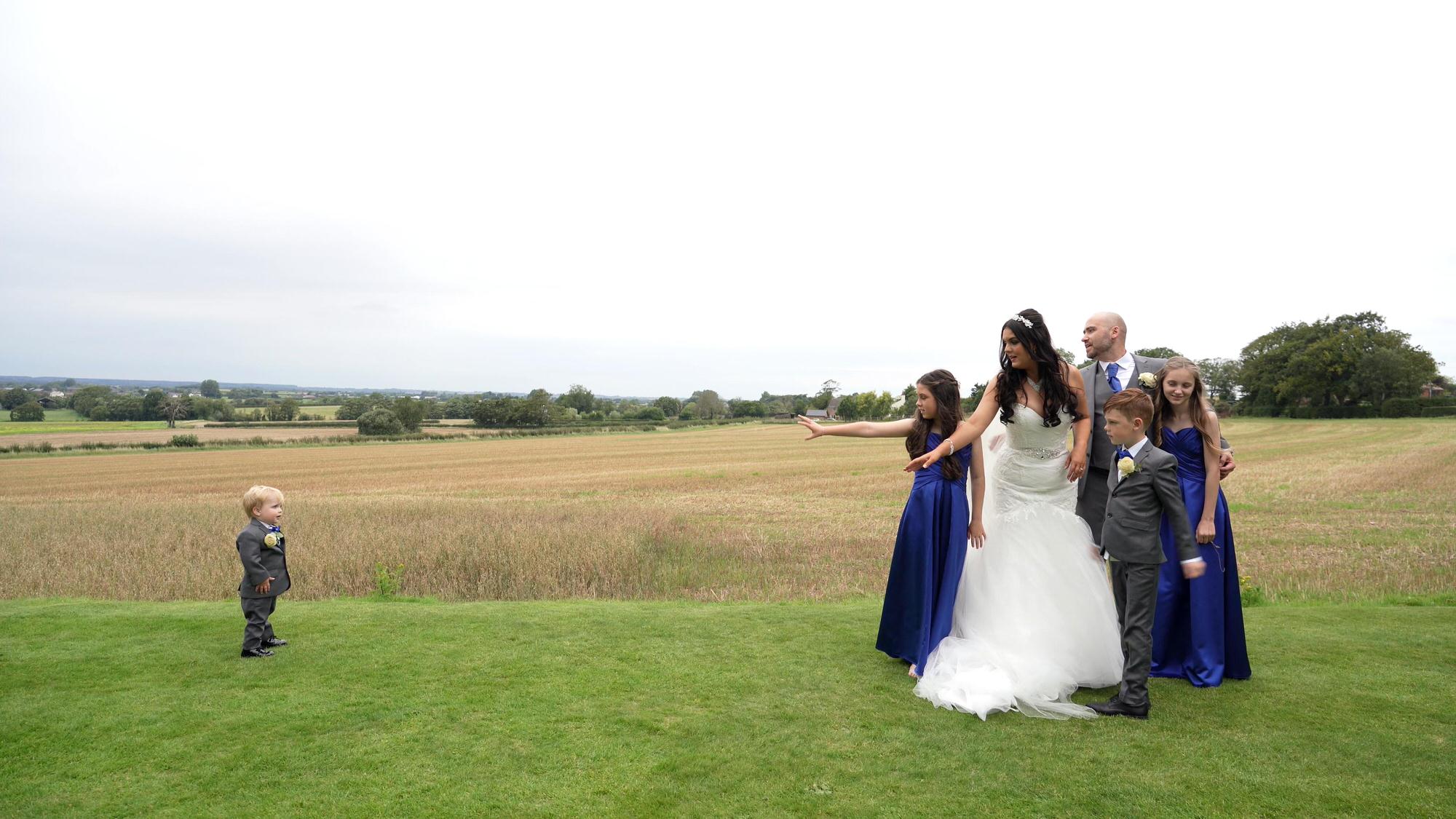 Nicola and Dans West Tower Wedding Video 24 the family reach out to tempt the baby in to a group photo at West Tower