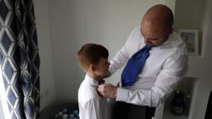 a groom ties his sons bow tie on the morning of his wedding