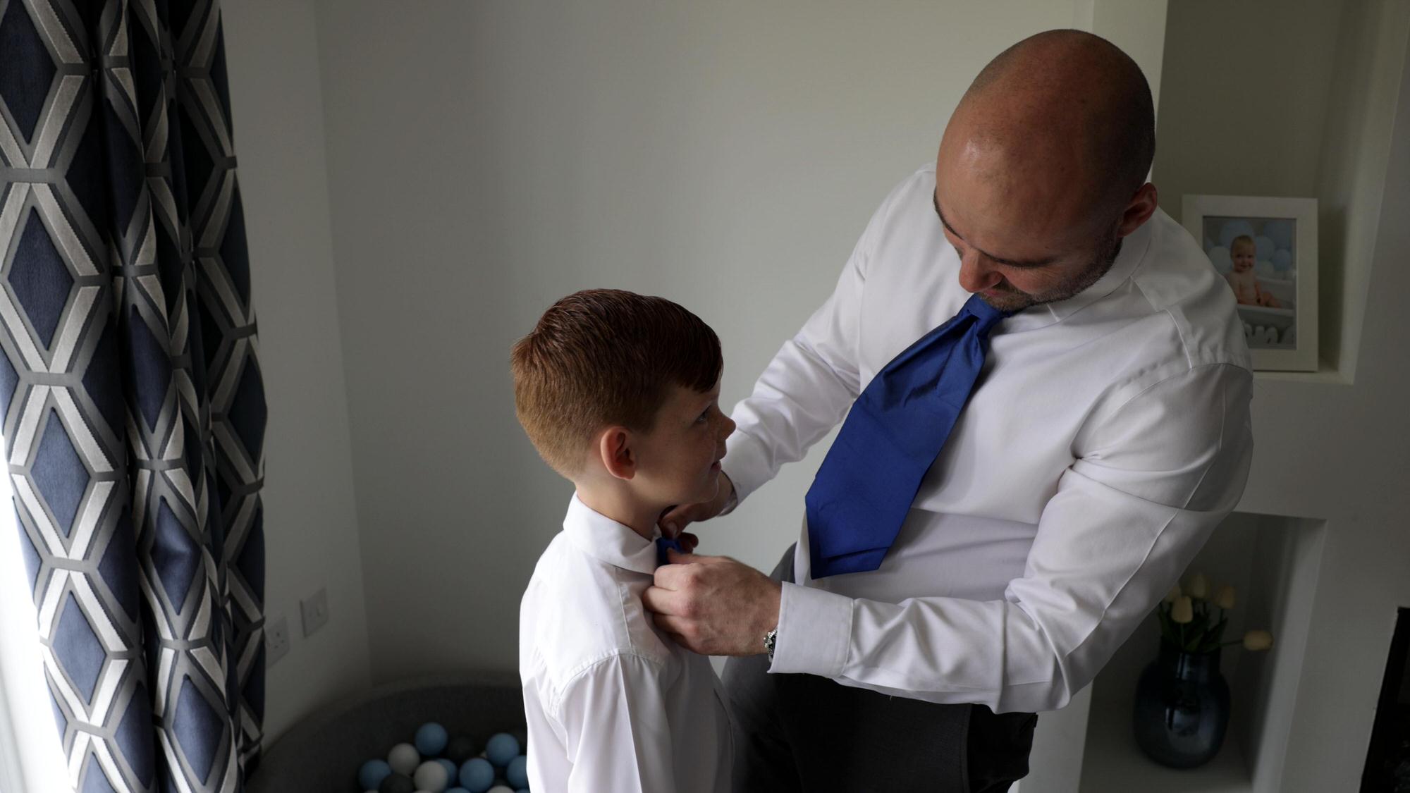 a groom ties his sons bow tie on the morning of his wedding